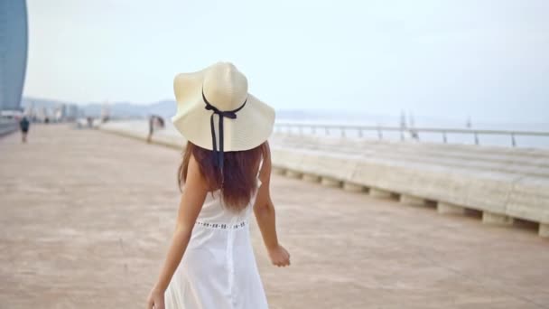 Mujer bonita con vestido blanco y sombrero de pamela caminando — Vídeo de stock