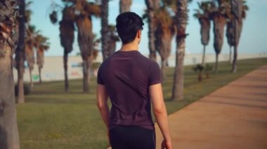 Genç atletik adam plaja yakın palmiye ağacı parkta yürüyüş
