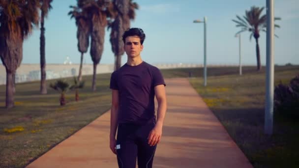 Νέος αθλητικός άνθρωπος περπάτημα στο φοινικόδασος κοντά στην παραλία — Αρχείο Βίντεο
