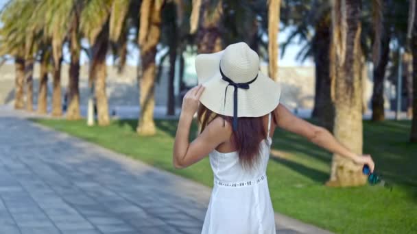 Mulher bonita vestindo vestido branco e chapéu pamela andando — Vídeo de Stock