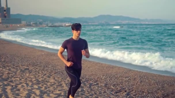 Un joven atlético corriendo en la playa. Concepto de salud — Vídeos de Stock