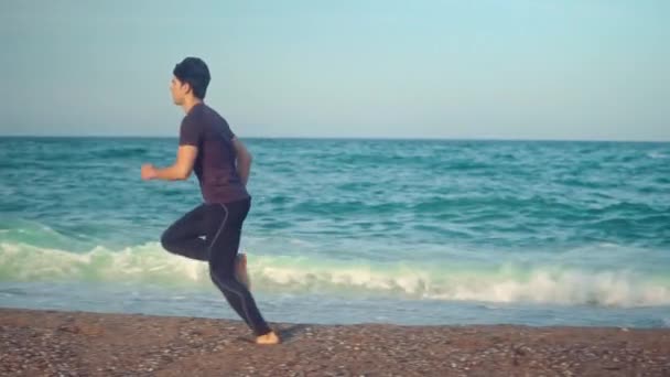 Молодой спортсмен бегает по пляжу. Концепция здоровья — стоковое видео
