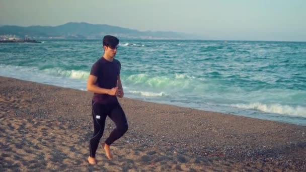 Mladý atletický muž, který běží na pláži. Koncepce zdraví — Stock video