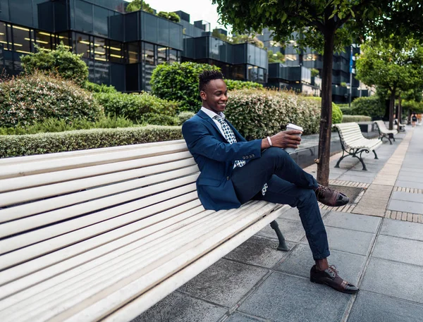 Empresário afro-americano que usa fato azul bebe café perto do escritório — Fotografia de Stock