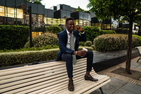 Empresário afro-americano segurando celular vestindo terno azul — Fotografia de Stock