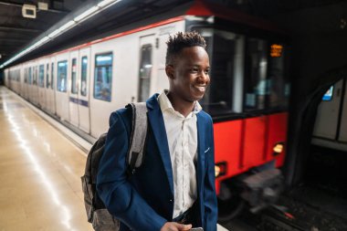 Mavi takım elbise ve sırt çantası giyen Afro-Amerikalı işadamı