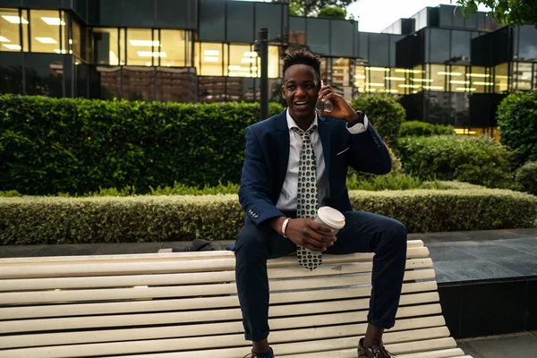Empresário afro-americano segurando celular vestindo terno azul — Fotografia de Stock