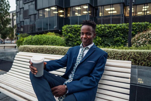 Hombre de negocios afroamericano con traje azul bebe café cerca de la oficina —  Fotos de Stock