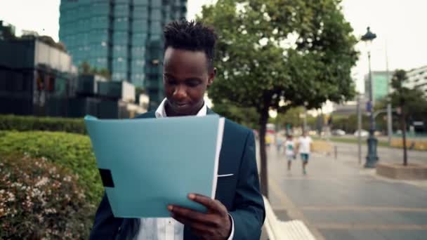 Hombre de negocios lee documentos o cuaderno con traje azul cerca de la oficina — Vídeo de stock