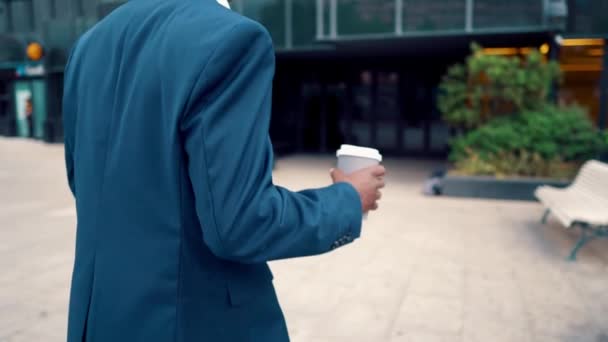 Hombre de negocios afroamericano con traje azul bebe café cerca de la oficina — Vídeo de stock