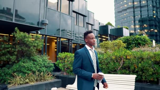 Empresário afro-americano que usa fato azul bebe café perto do escritório — Vídeo de Stock