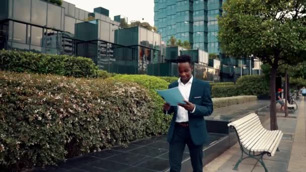 Hombre de negocios lee documentos o cuaderno con traje azul cerca de la oficina — Vídeo de stock