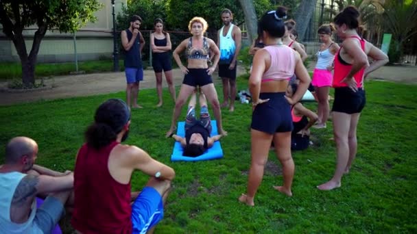 Uma lição de grupo sobre acroyoga que ocorre no parque — Vídeo de Stock