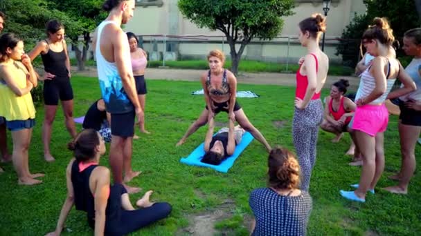 Uma lição de grupo sobre acroyoga que ocorre no parque — Vídeo de Stock