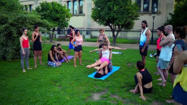 Uma lição de grupo sobre acroyoga que ocorre no parque — Vídeo de Stock