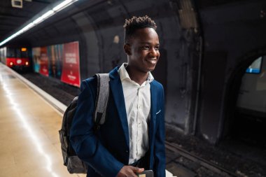 Mavi takım elbise ve sırt çantası giyen Afro-Amerikalı işadamı