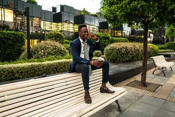 Uomo d'affari afroamericano in possesso di cellulare con indosso abito blu — Foto Stock