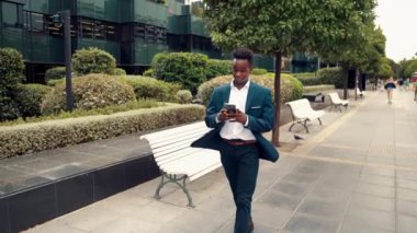 Mavi takım elbise giyen cep telefonu tutan Afro-Amerikalı işadamı