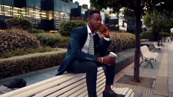 Afrikansk amerikansk affärsman som innehar mobiltelefon klädd i blå kostym — Stockvideo