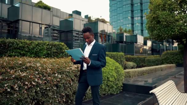 Hombre de negocios lee documentos o cuaderno con traje azul cerca de la oficina — Vídeo de stock