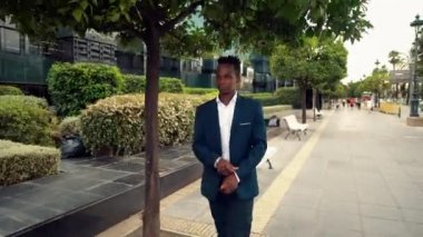 Mavi takım elbise giyen Afro-Amerikan işadamı yürüyor