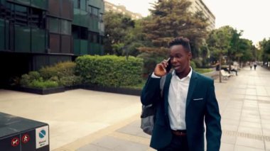 Mavi takım elbise giyen cep telefonu tutan Afro-Amerikalı işadamı
