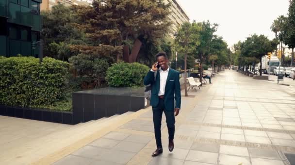 Афроамериканский бизнесмен держит мобильный телефон в синем костюме — стоковое видео