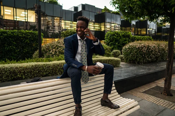 Empresário afro-americano segurando celular vestindo terno azul — Fotografia de Stock