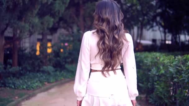 Азиатская девушка в белом платье прогуливается по парку — стоковое видео