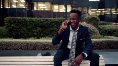 Mavi takım elbise giyen cep telefonu tutan Afro-Amerikalı işadamı