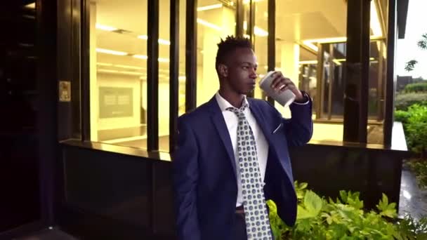 Hombre de negocios afroamericano con traje azul bebe café cerca de la oficina — Vídeos de Stock