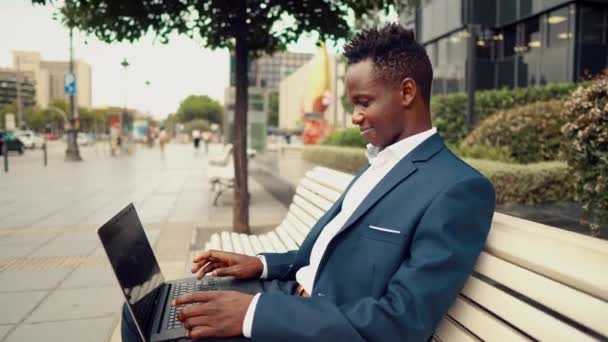 Hombre de negocios afroamericano sosteniendo portátil portátil con traje azul — Vídeos de Stock