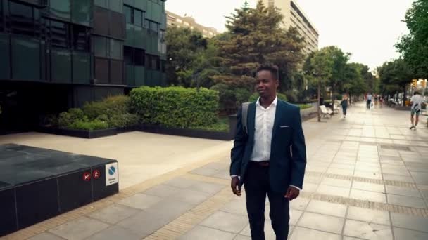 青いスーツを着たアフリカ系アメリカ人のビジネスマンが歩く — ストック動画
