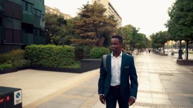 Mavi takım elbise giyen Afro-Amerikan işadamı yürüyor