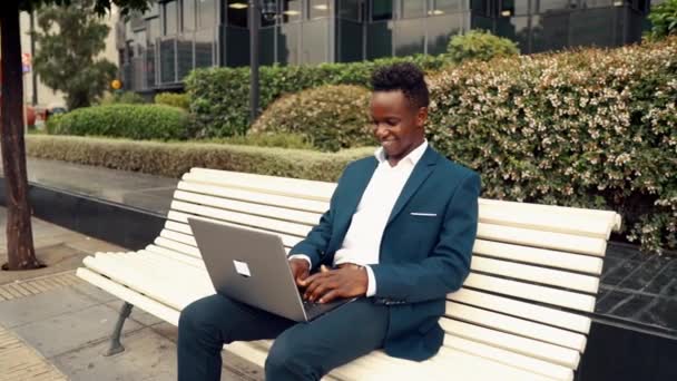 Hombre de negocios afroamericano sosteniendo portátil portátil con traje azul — Vídeos de Stock