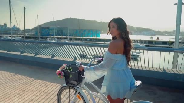 青いドレスを着たアジアのモデルは、海のテラスで白い自転車に乗ります — ストック動画