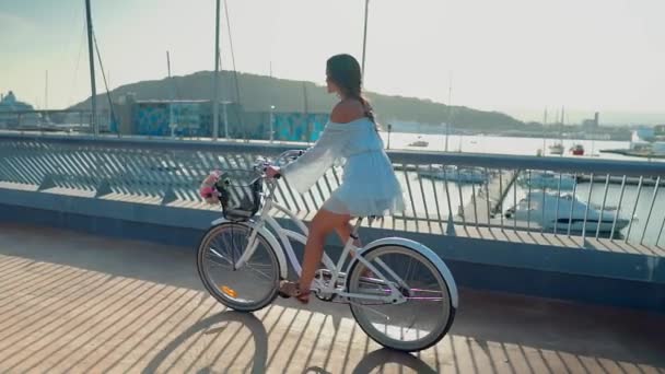 Modello asiatico in un abito blu cavalca una bicicletta bianca sulla terrazza sul mare — Video Stock