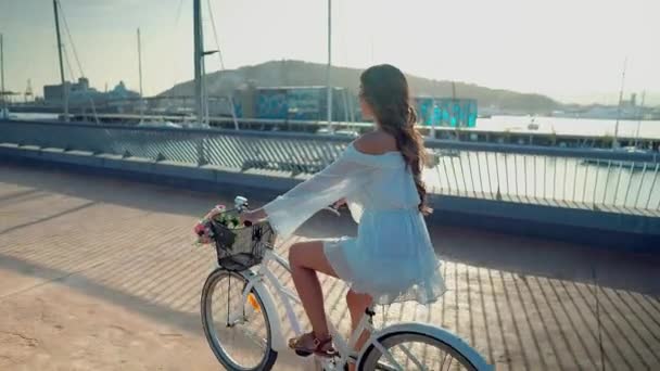 Modelo asiático em um vestido azul monta uma bicicleta branca no terraço do mar — Vídeo de Stock