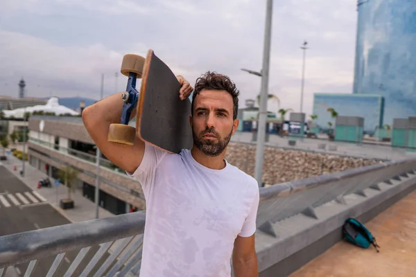 Skateboarder stoi na deskorolce na nowoczesnym tarasie miejskim — Zdjęcie stockowe