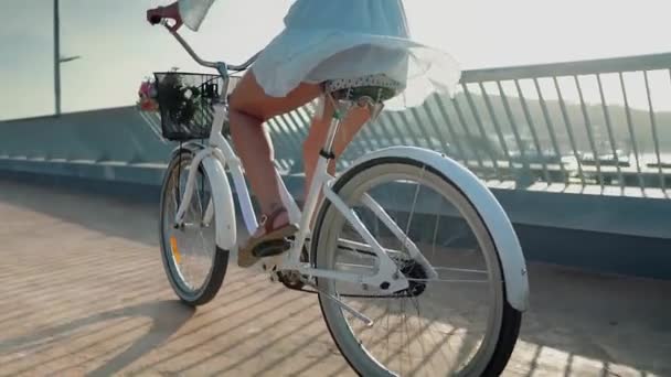 Mavi elbiseli Asyalı model deniz terasında beyaz bir bisiklete biniyor — Stok video