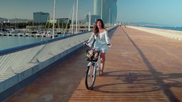 Asiatisk modell i en blå klänning rider en vit cykel på havet terrass — Stockvideo