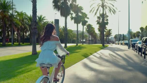 Asian model in a blue dress rides a white bicycle in a green park — Stock Video