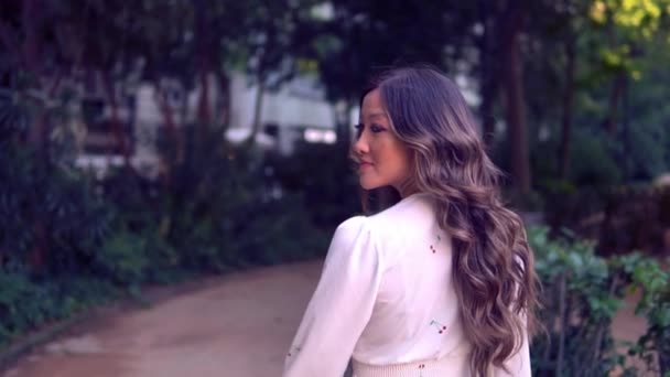 Hermosa chica asiática en vestido blanco caminando en el parque — Vídeos de Stock