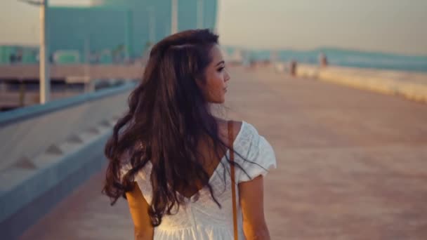 Hermosa chica en el vestido blanco caminando a lo largo del paseo marítimo — Vídeos de Stock