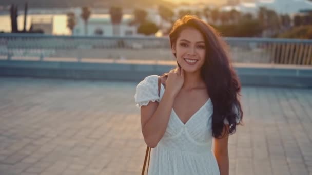 Mooi meisje in de witte jurk wandelen langs de zeepromenade — Stockvideo