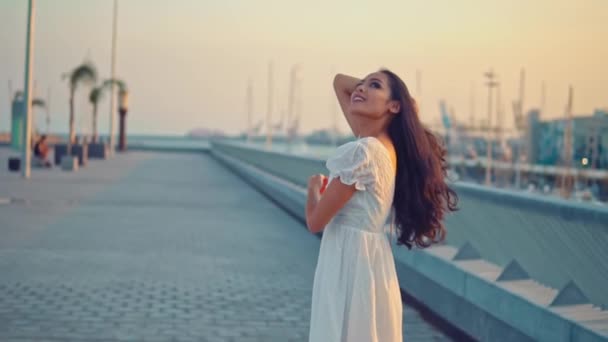 Hermosa chica en el vestido blanco caminando a lo largo del paseo marítimo — Vídeos de Stock