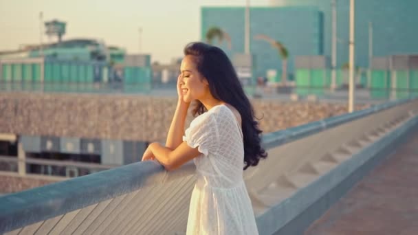 Девушка в белом платье, стоящая на террасе на морской набережной — стоковое видео