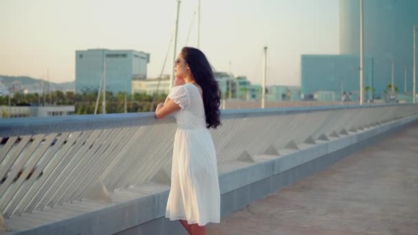 Hermosa chica en el vestido blanco caminando a lo largo del paseo marítimo — Vídeos de Stock