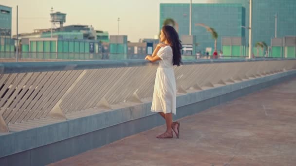 女孩穿着白色礼服站在海上长廊露台 — 图库视频影像