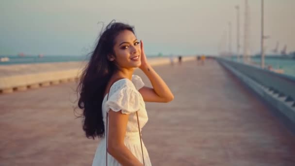 Hermosa chica en el vestido blanco caminando a lo largo del paseo marítimo — Vídeo de stock